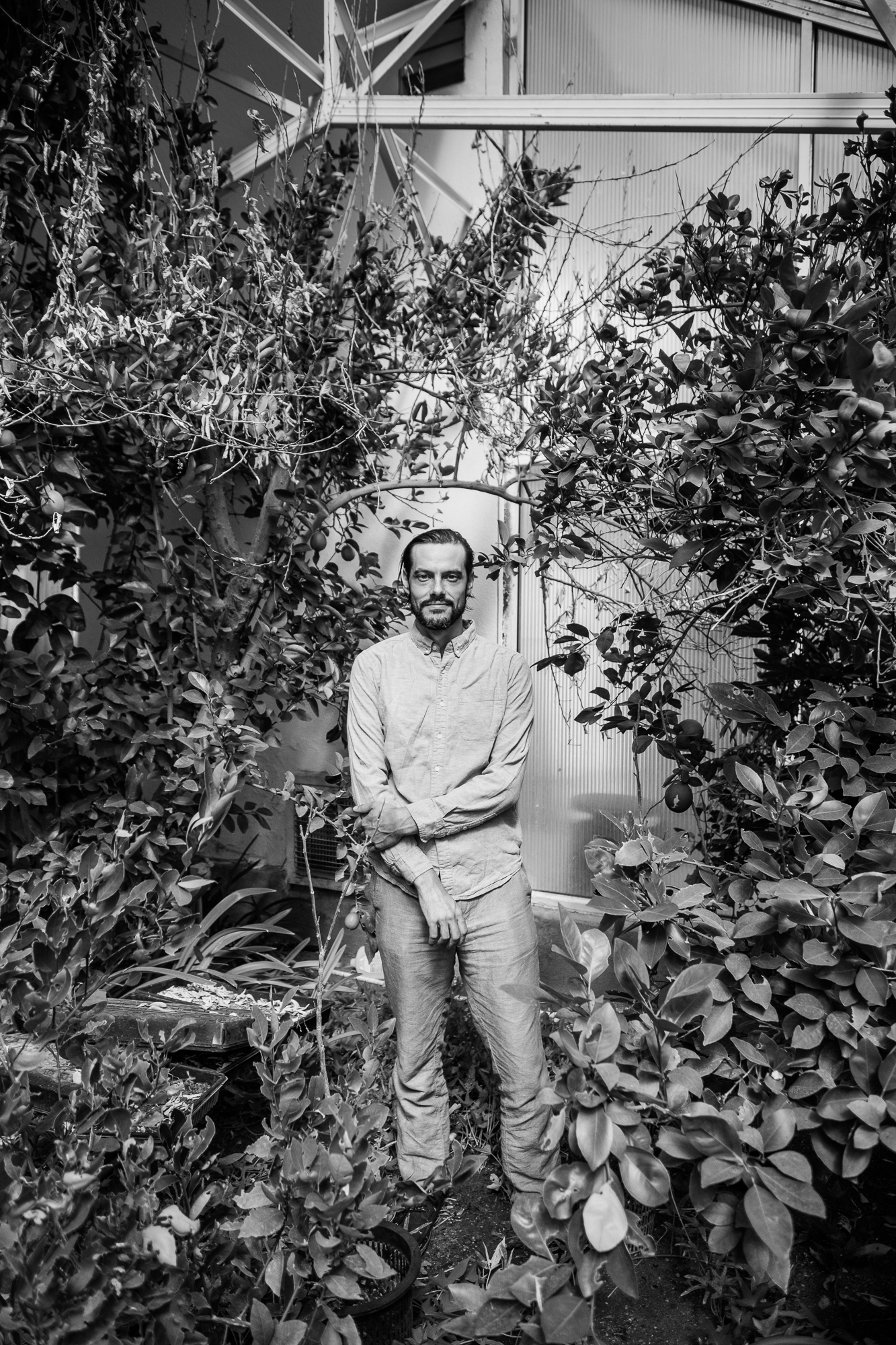 a man stands in a greenhouse surrounded by plants